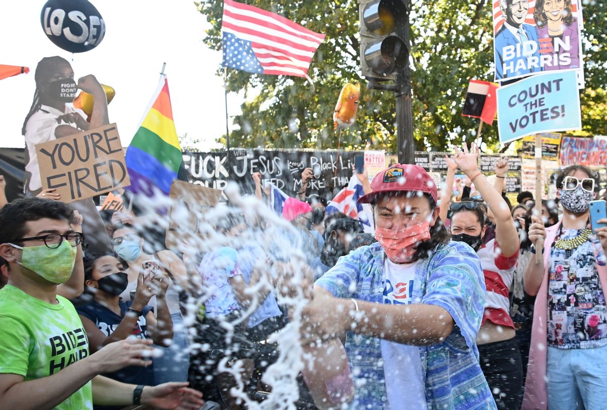 A woman sprays prosecco onto the crowd as people celebrate on Black Lives Matter plaza across from the White House in Washington, DC on November 7, 2020, after Joe Biden was declared the winner of the 2020 presidential election. (MANDEL NGAN/AFP via Getty Images)