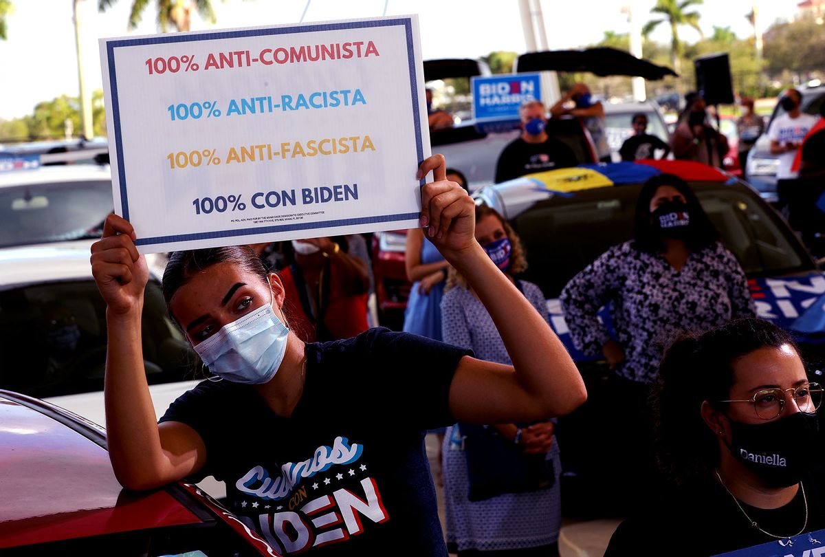 Wearing a face masks to reduce the risk posed by the coronavirus, Sophia Hildalgo (L) and Amore Rodriguez of Miami stay with their car decorated in Cubans for Biden paint as Democratic presidential nominee Joe Biden delivers remarks during a drive-in voter mobilization event at Miramar Regional Park October 13, 2020 in Miramar, Florida. (Chip Somodevilla/Getty Images)