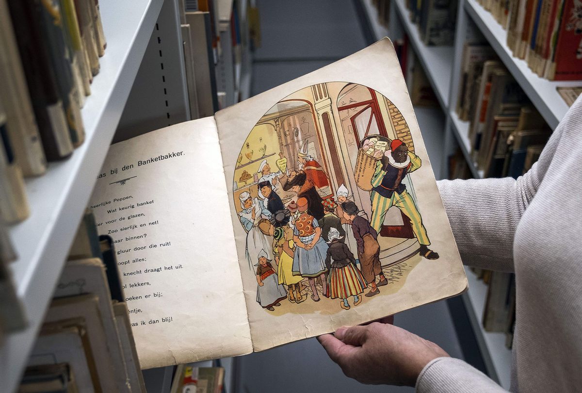 An employee of the Amsterdam Public Library (OBA) shows a book with Sinterklaas and Zwarte Piet (Black Pete) in Amsterdam, on November 12, 2020 - The library is removing books with traditional Zwarte Piet from the museum to a safe. (RAMON VAN FLYMEN/ANP/AFP via Getty Images)