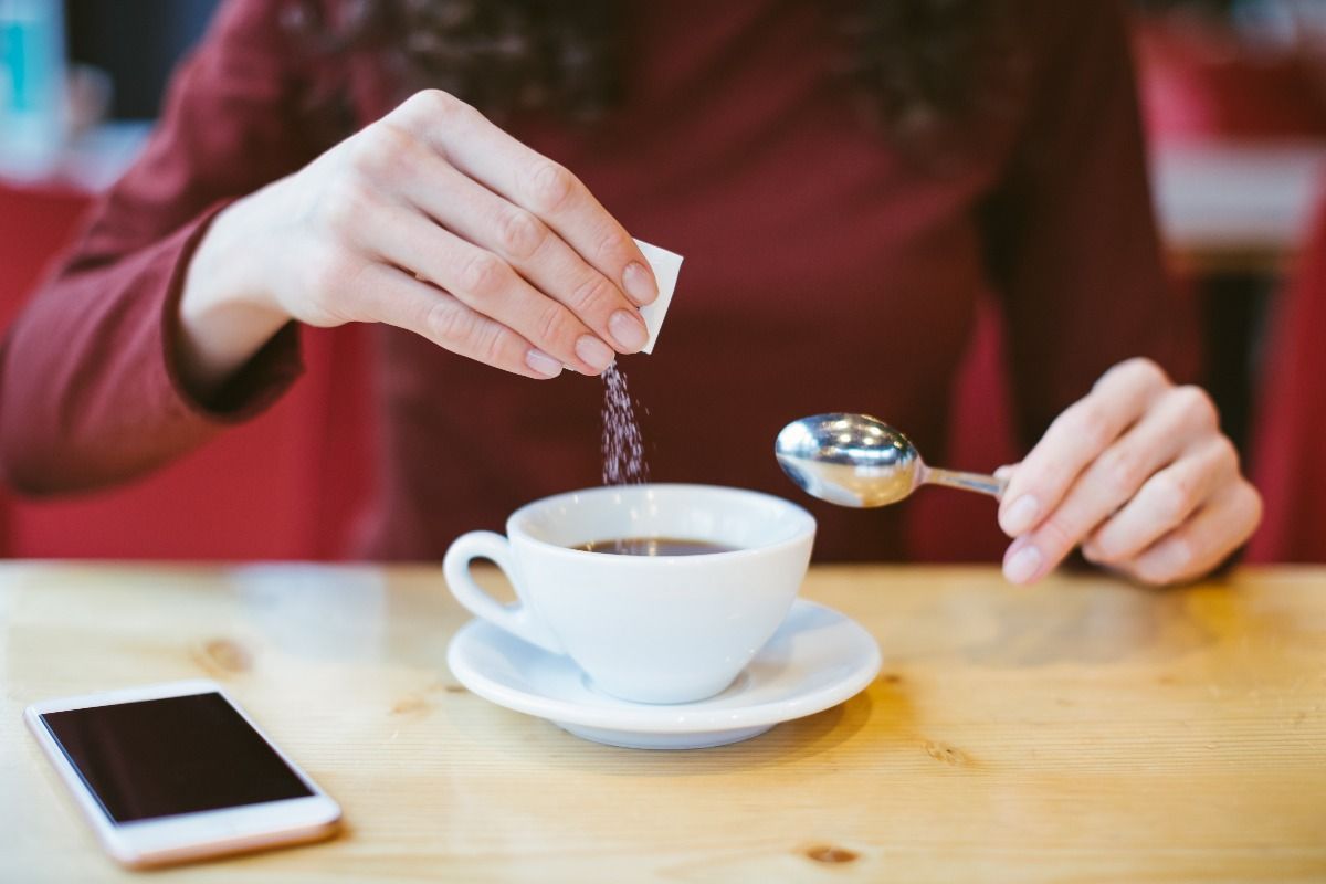 Woman's hands pouring sugar into black coffee. (Getty Images)