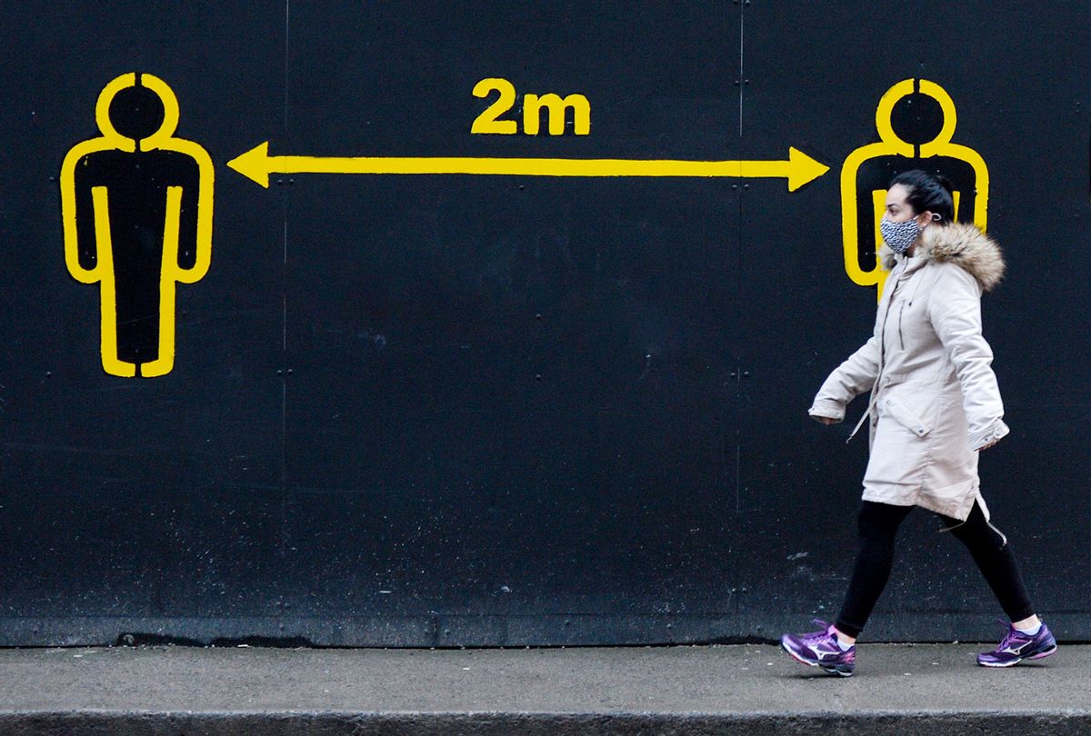A woman walks by a sign 2metres in Dublin city centre during Level 5 Covid-19 lockdown. The Department of Health reported this evening 2,001 of new Covid-19 cases for the Republic of Ireland and 93 deaths, a new record for a confirmed number of daily deaths. On Tuesday, 19 January, 2021, in Dublin, Ireland. (Artur Widak/NurPhoto via Getty Images)