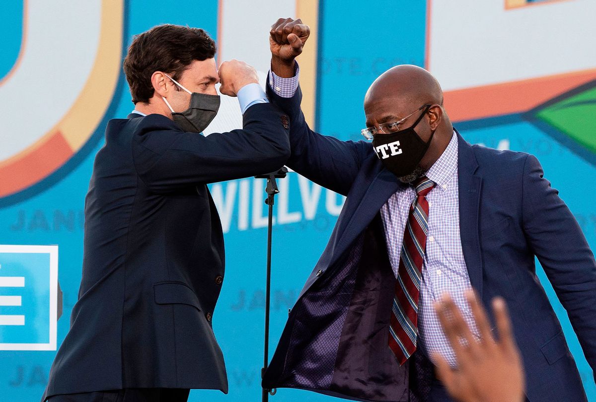 Democratic candidates for Senate Jon Ossoff (L) and Raphael Warnock (R) bump elbows on stage during a rally with US President-elect Joe Biden outside Center Parc Stadium in Atlanta, Georgia, on January 4, 2021. (JIM WATSON/AFP via Getty Images)