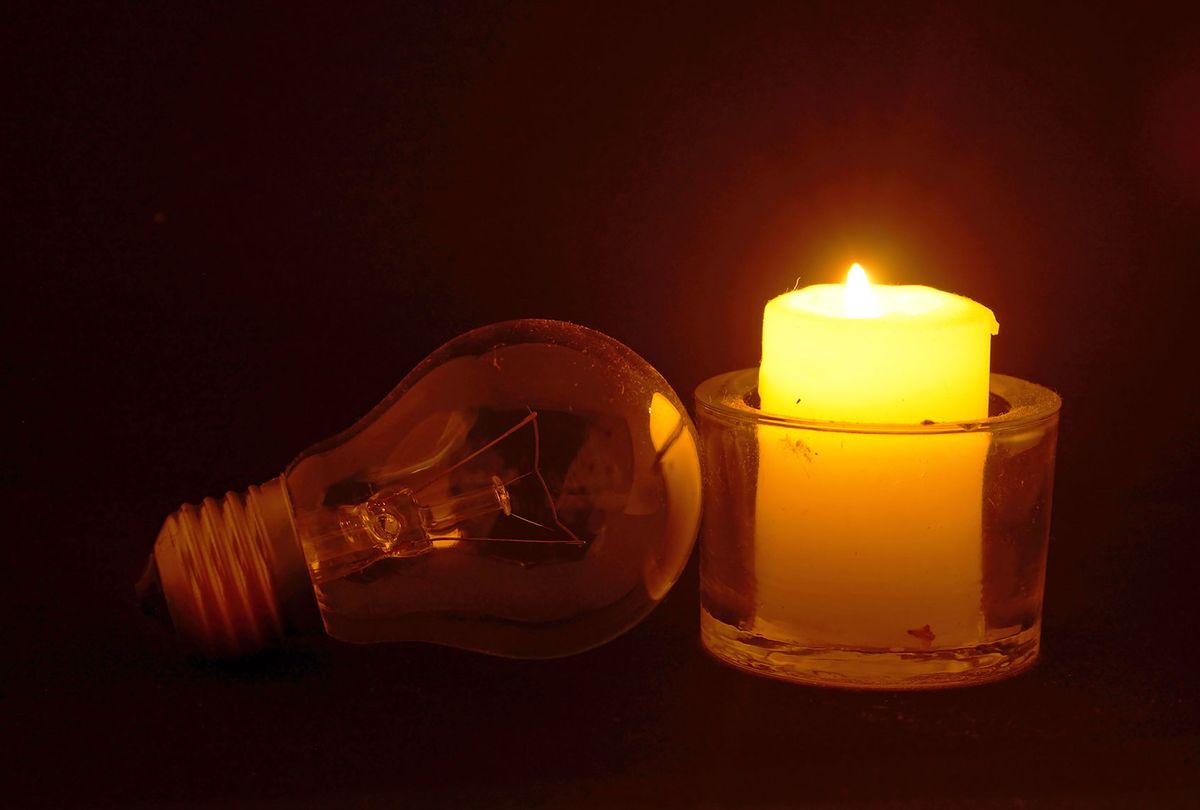 Burning candle on desktop in darkness (Getty Images)
