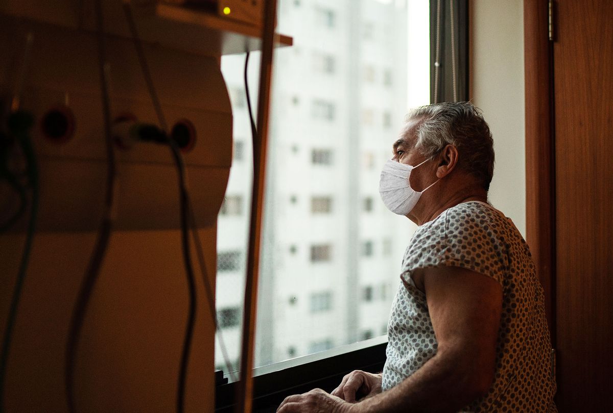 A senior patient using a mask looking through the window at the hospital (Getty Images)