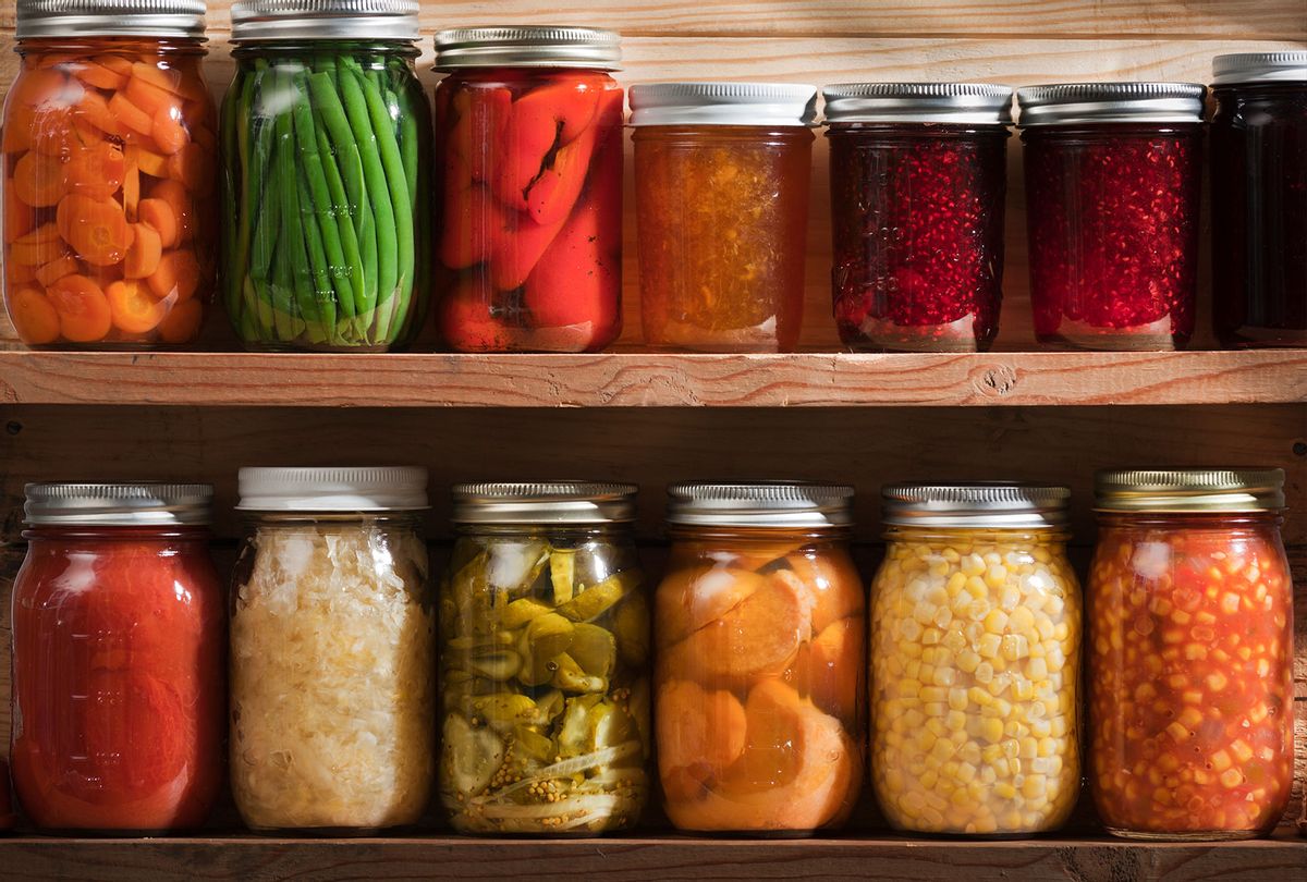 Two wooden shelves holding a variety of canned vegetables and fruits, lined up in rows of glass jars. (Getty Images)