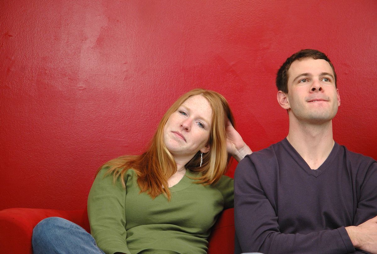 Young guy and girl sitting on a couch looking bored (Getty Images)