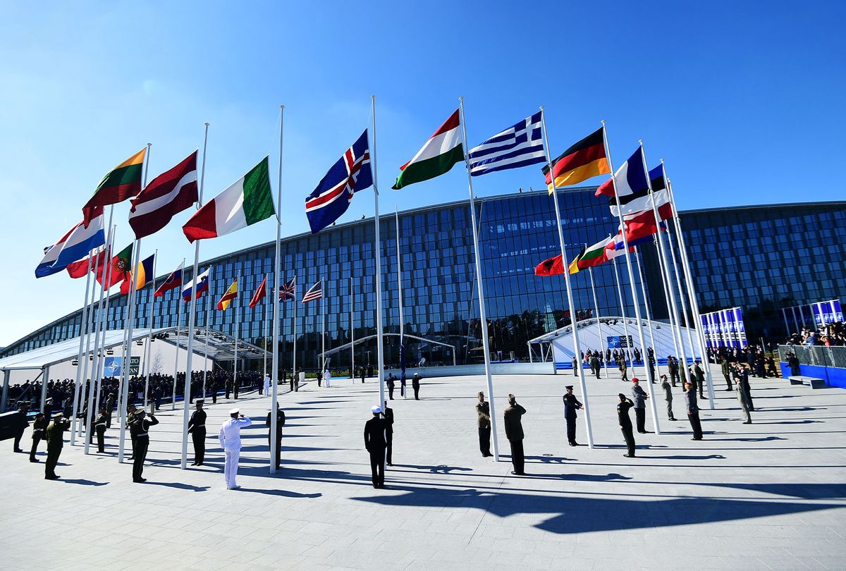 Officials and military personnel stand beneath flags as they attend the NATO (North Atlantic Treaty Organization) summit ceremony at the NATO headquarters, in Brussels (EMMANUEL DUNAND/AFP via Getty Images)