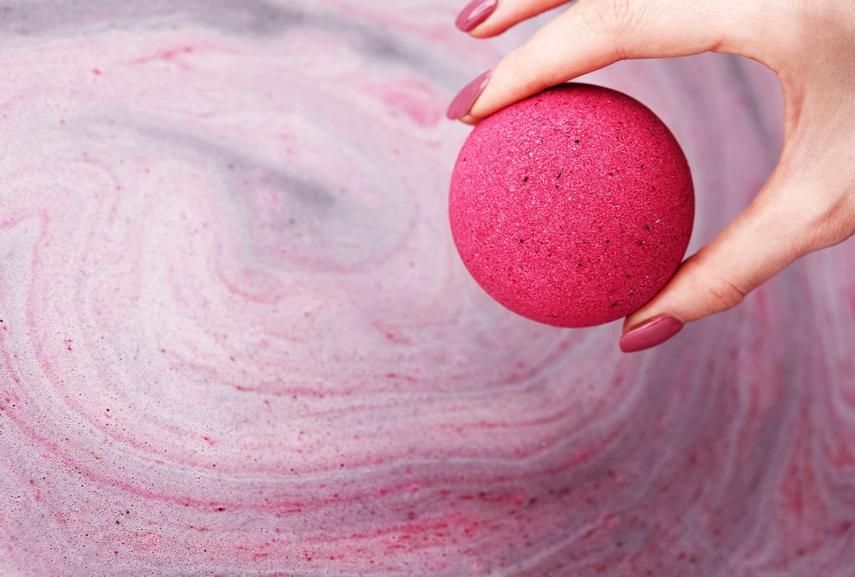 Woman's hand putting bath bomb into water (Getty Images)