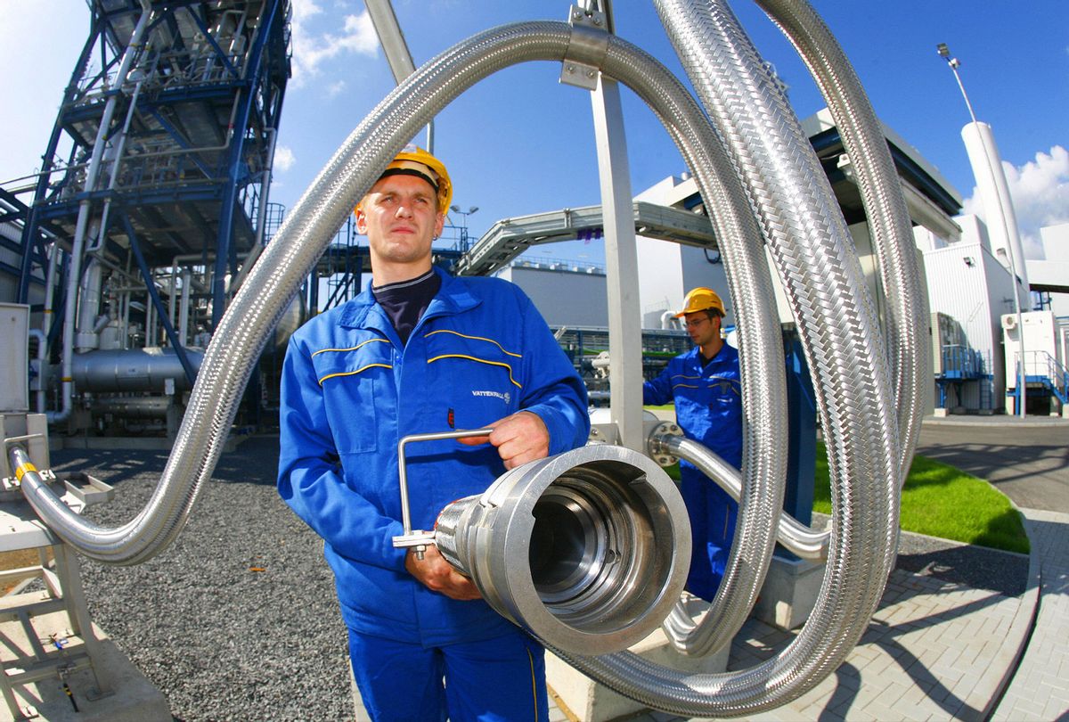 An employee poses with a pipe used to carrying liquid CO2 on September 08, 2008 at the "Schwarze Pumpe" ("Black Pump") power station run by Europe's biggest power company Vattenfall in Werder near Berlin. In a similar manner, Summit Carbon Solutions, a spinoff of an Iowa-based agricultural company, recently announced it is developing a $2 billion pipeline project that will carry carbon dioxide captured from ethanol refineries scattered across the Midwest to a site in North Dakota where it will be pumped thousands of feet underground. (MICHAEL URBAN/DDP/AFP via Getty Images)
