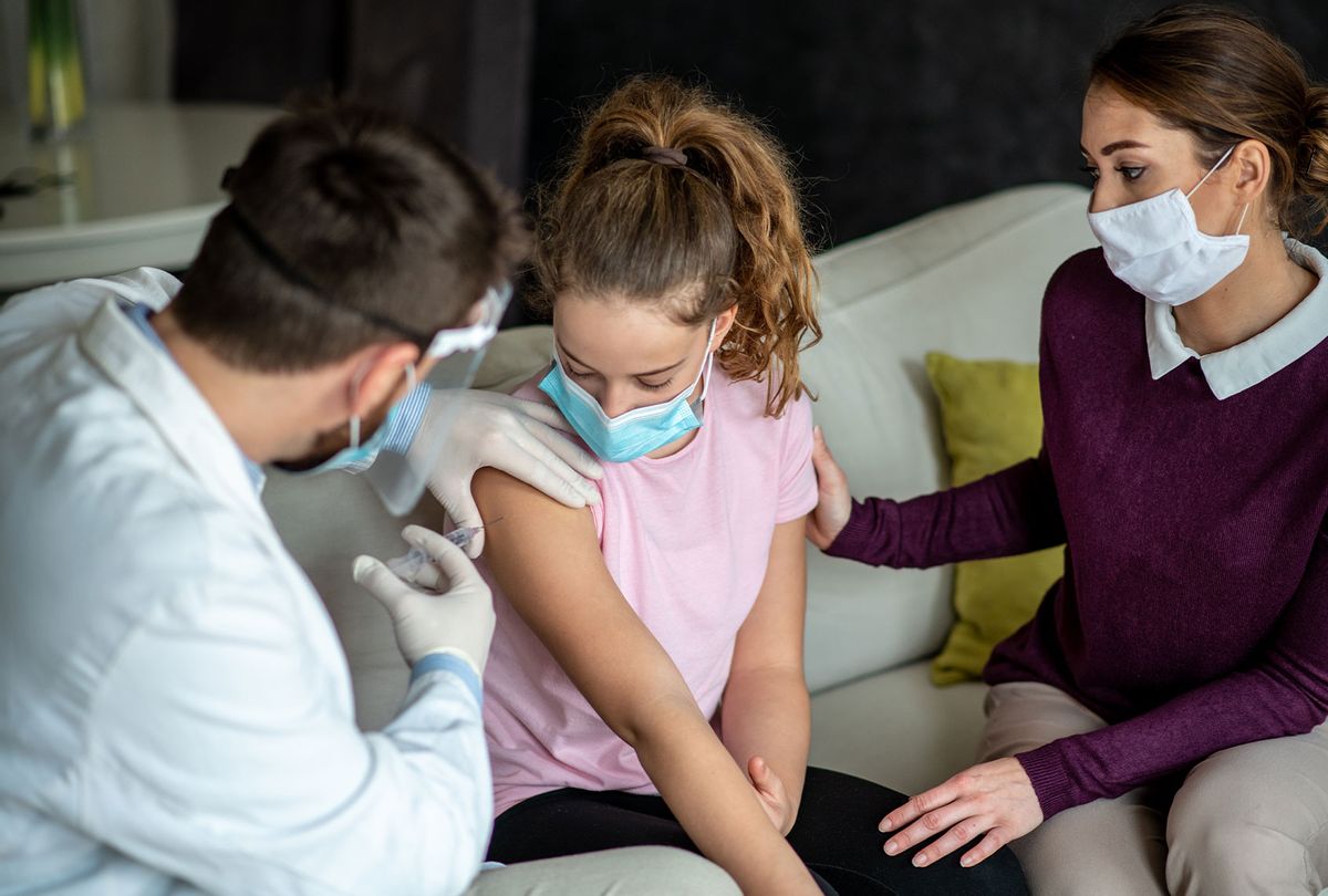 Young girl is sitting and taking vaccine shot to her shoulder, with her mother who is encouraging her, and doctor who is giving her vaccine. (Getty Images)