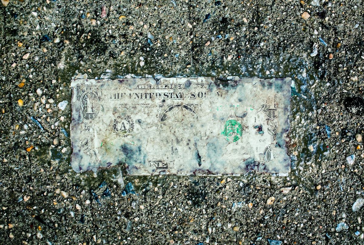 Deteriorating one dollar bill on wet pavement (Getty Images)