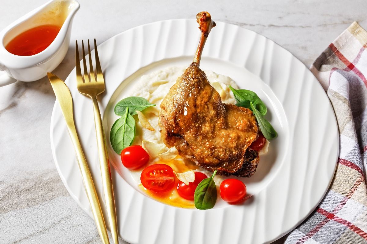 Duck confit with parsnip purée, orange sauce cherry tomatoes and fresh spinach leaves. (Getty Images)