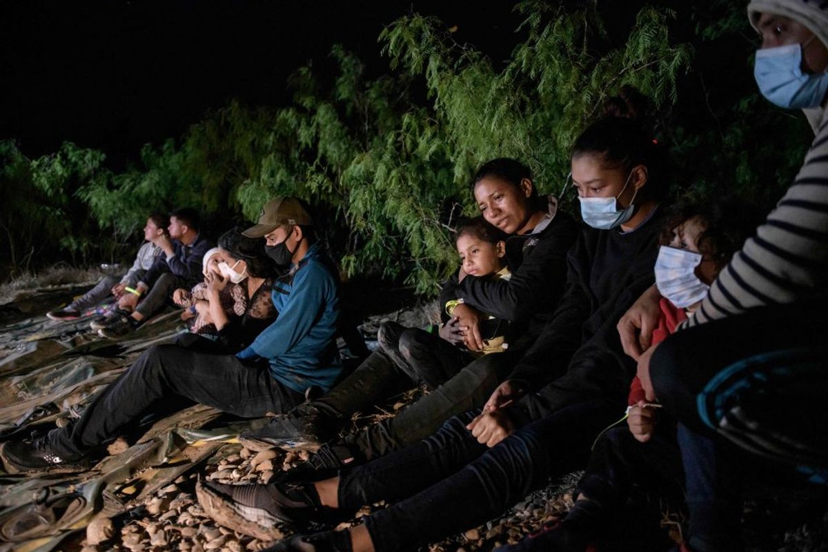 Immigrants from Honduras who arrived across the Rio Grande river from Mexico rest on the U.S. side of the river on March 27, 2021, following their crossing, before making their way towards a makeshift processing checkpoint. (Ed Jones/AFP via Getty Images)