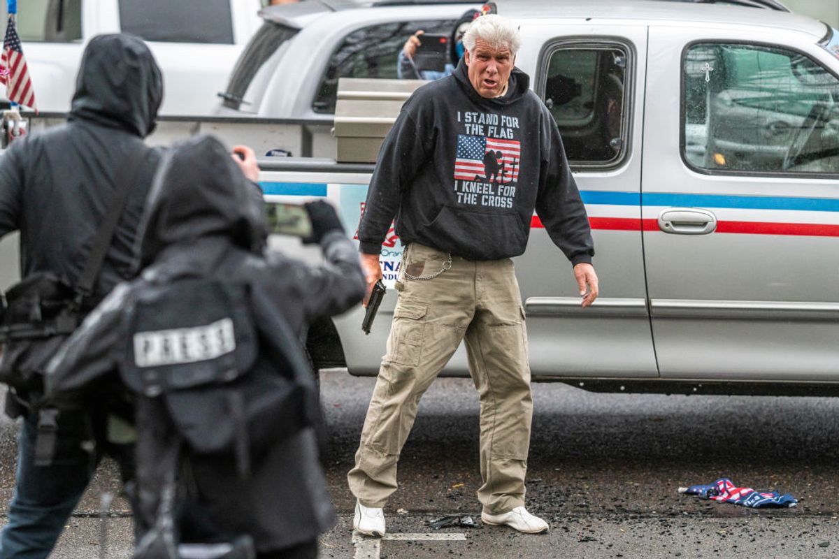 A driver pulls a handgun on protesters after they allegedly broke his truck's lights on March 28, 2021, in Salem, Oregon. The protesters clashed with occupants of vehicles that had participated in an American flag-waving car caravan, despite law enforcement efforts to keep the groups separate. (Nathan Howard/Getty Images)