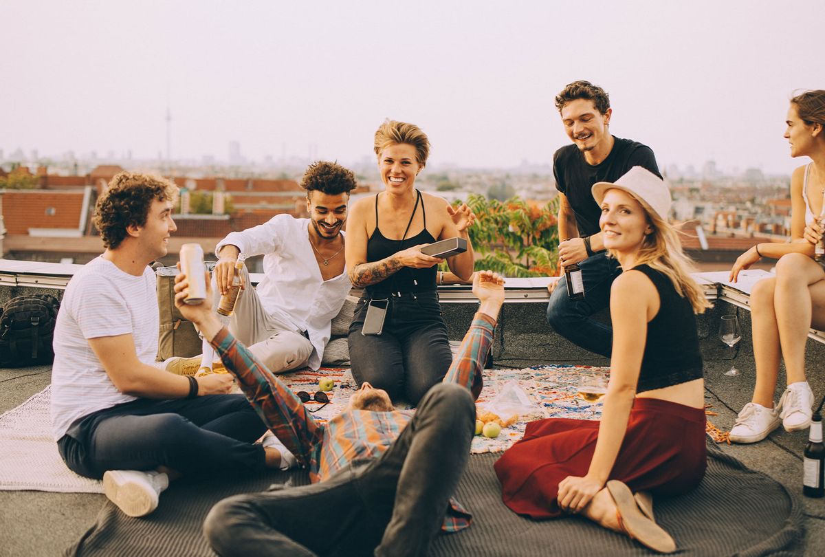 Friends enjoying music on speaker during rooftop party at terrace against sky (Getty Images)