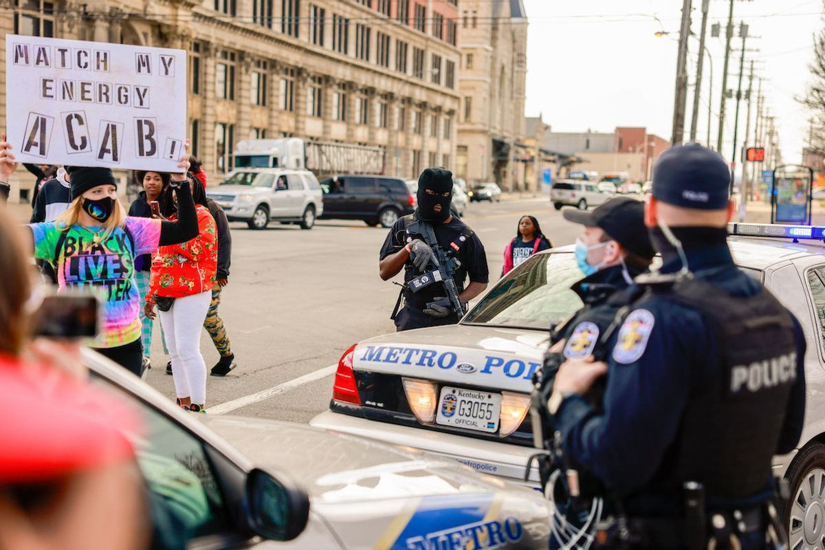 A protester holding a placard expressing her opinion in front of police during a memorial march to mark the one year anniversary since the Louisville Metro Police Department shot and killed Breonna Taylor at her home in Louisville.  (Jeremy Hogan/SOPA Images/LightRocket via Getty Images)