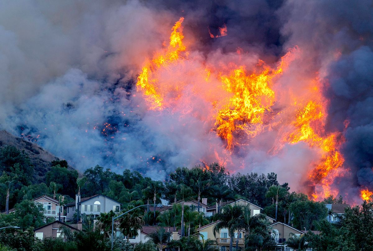 Flames rise near homes during the Blue Ridge Fire on October 27, 2020 in Chino Hills, California. Strong Santa Ana Winds gusting to more than 90 miles per hour have driven the Blue Ridge Fire and Silverado Fire across thousands of acres, grounding firefighting aircraft, forcing tens of thousands of people to flee, and gravely injuring two firefighters. More than 8,200 wildfires have burned across a record 4 million-plus acres so far this year, more than double the previous record. (David McNew/Getty Images)