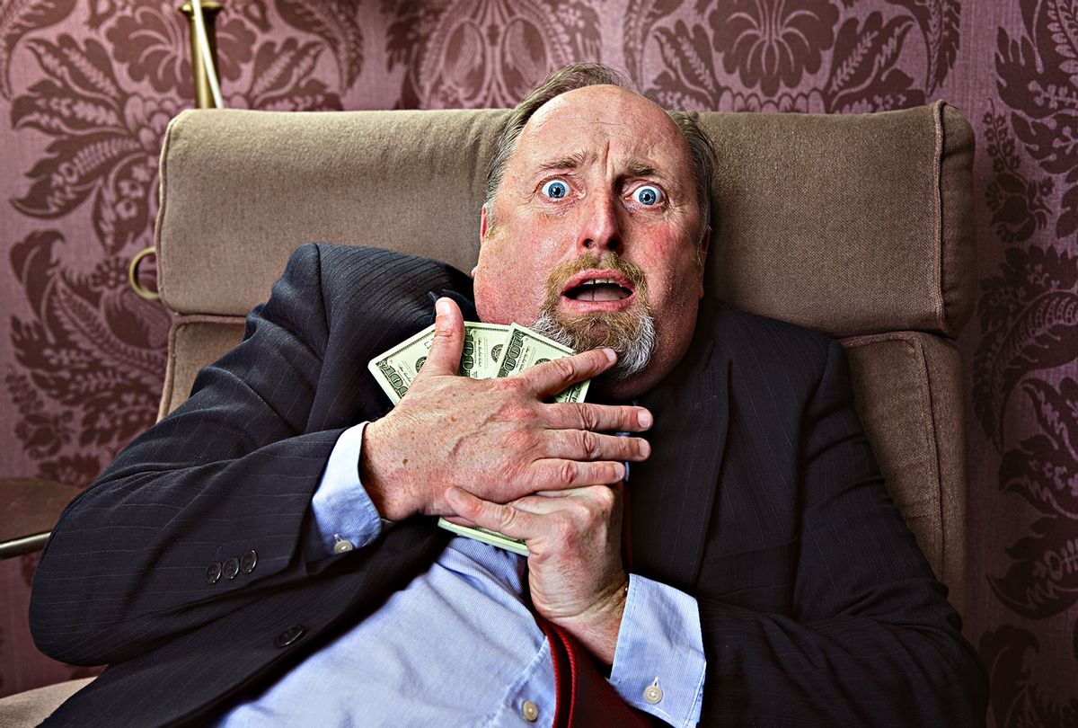 Middle aged man hugging US dollars with a frightened facial expression (Getty Images)