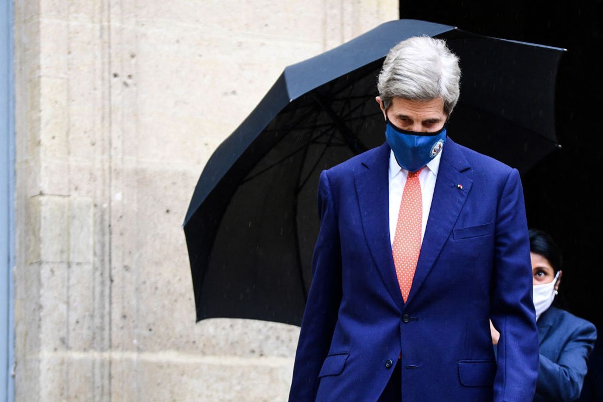 A member of staff holds the umbrella for US climate envoy John Kerry as he leaves the Hotel Roquelaure following his meeting French Ecological Transition Minister, in Paris, on March 11, 2021. (Photo by MARTIN BUREAU/AFP via Getty Images)