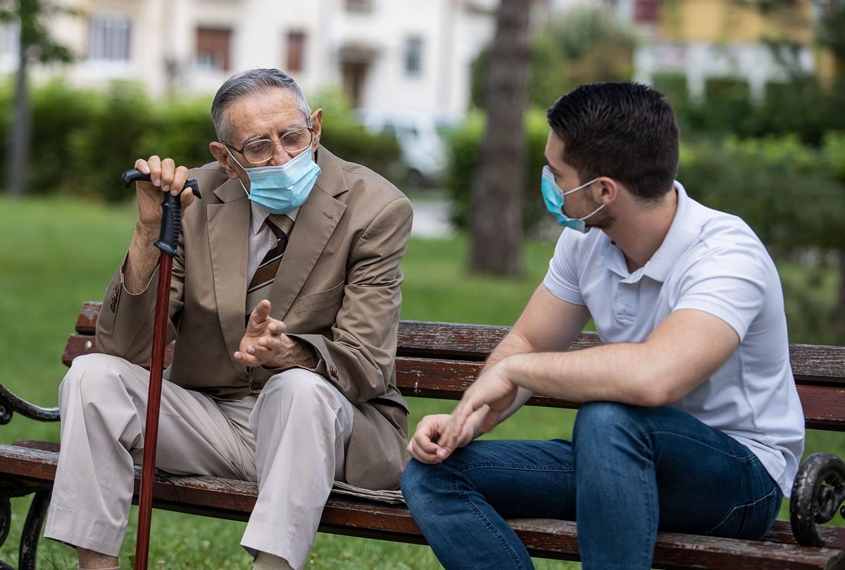 Old man and young man talking in the park, wearing masks (Getty Images)