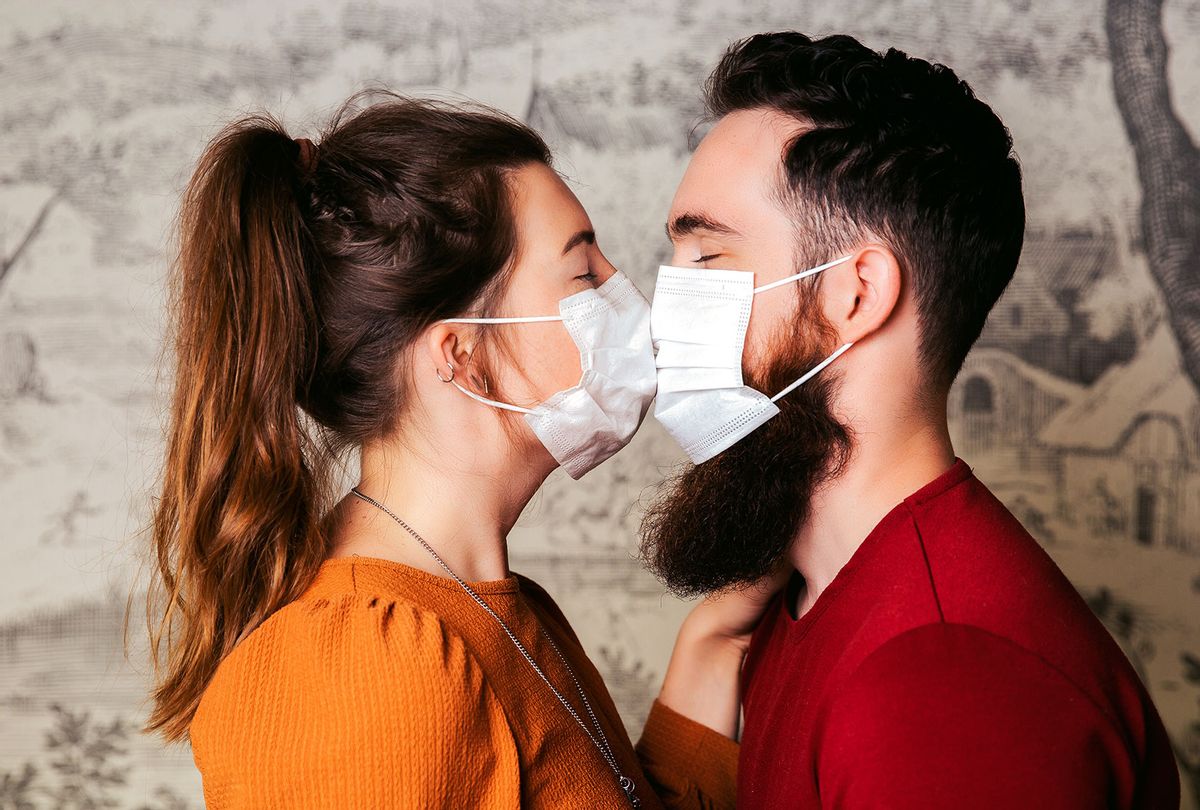 Side View Of Young Couple Wearing Masks Kissing Against Wall (Getty Images)