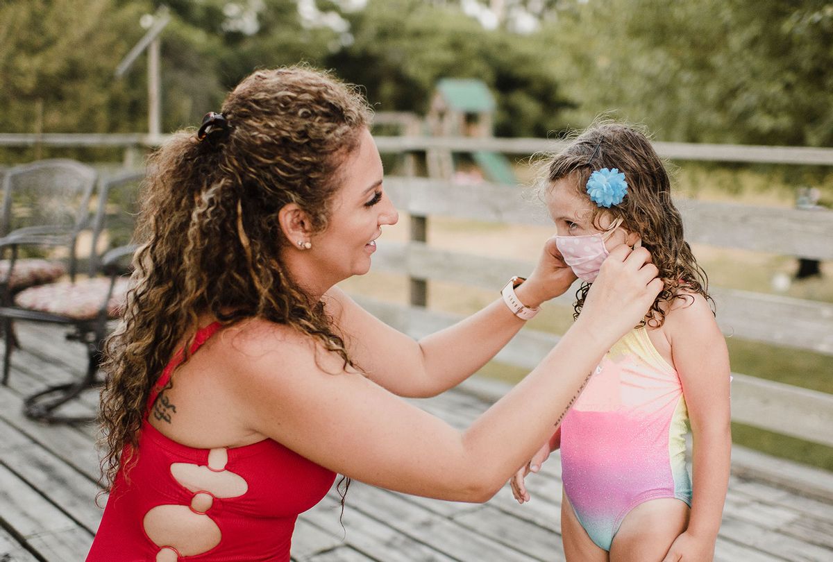 Mother in swimsuit applying protective face mask on daughter (Getty Images)