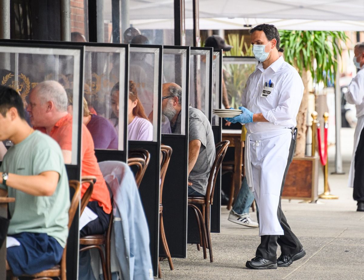 NEW YORK, NEW YORK: A waiter wears a face mask and rubber gloves outside Peter Luger Steakhouse in Williamsburg. (Photo by Noam Galai/Getty Images)