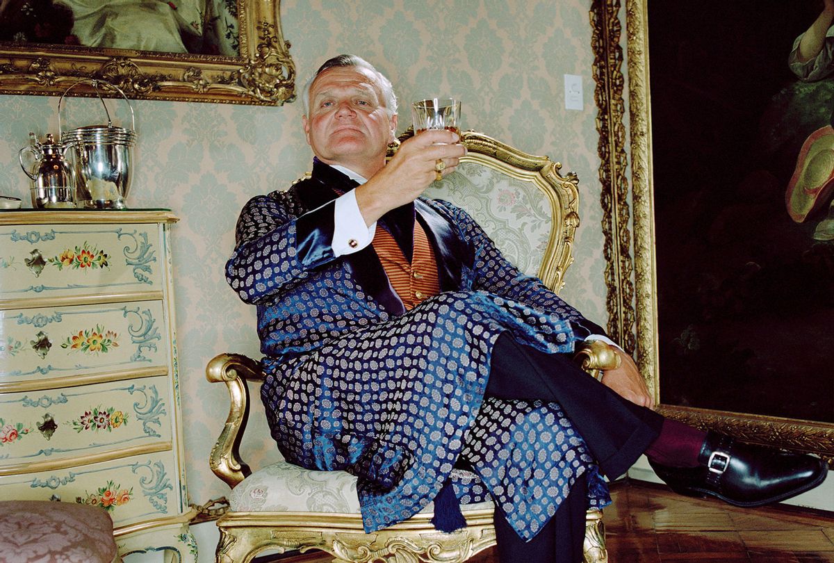 Rich man wearing smoking jacket raising glass, portrait (Getty Images)