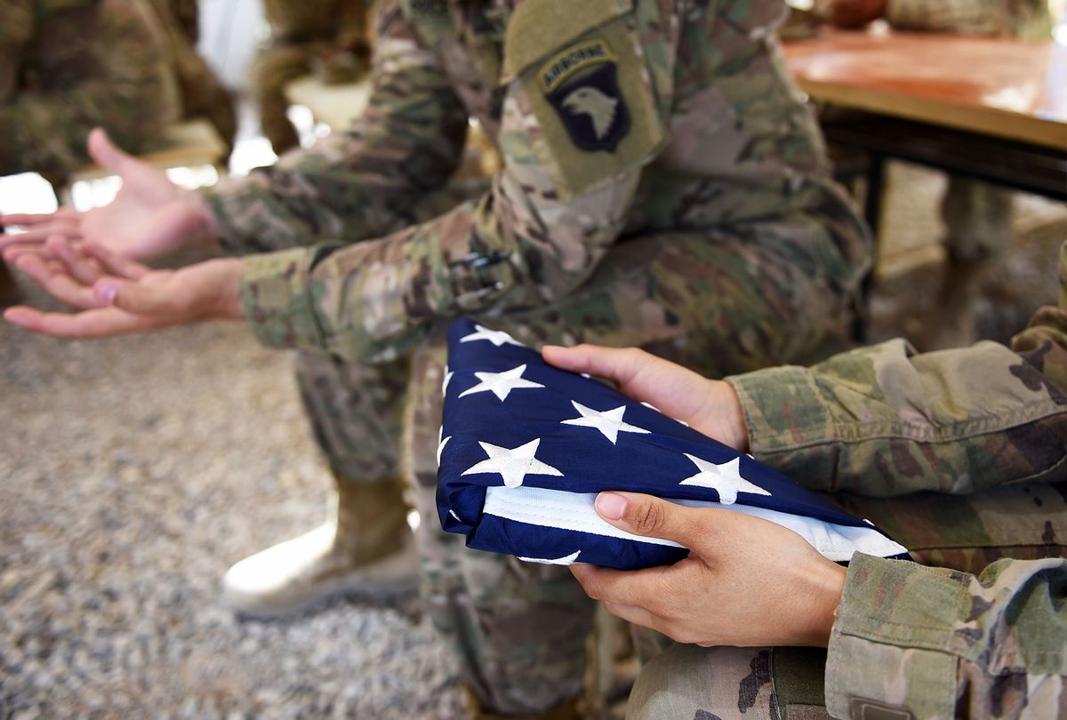 A US soldier holds the national flag ahead of a handover ceremony at Leatherneck Camp in Lashkar Gah in the Afghan province of Helmand on April 29, 2017. US Marines returned to Afghanistan's volatile Helmand April 29, where American troops faced heated fighting until NATO's combat mission ended in 2014, as embattled Afghan security forces struggle to beat back the resurgent Taliban. The deployment of some 300 Marines to the poppy-growing southern province came one day after the militants announced the launch of their "spring offensive", and as the Trump administration seeks to craft a new strategy in Afghanistan. (WAKIL KOHSAR/AFP via Getty Images)