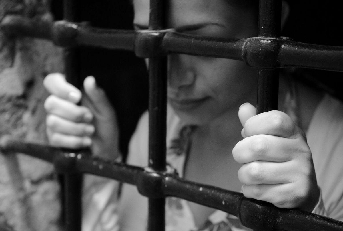 Young woman behind prison bars (Getty Images)