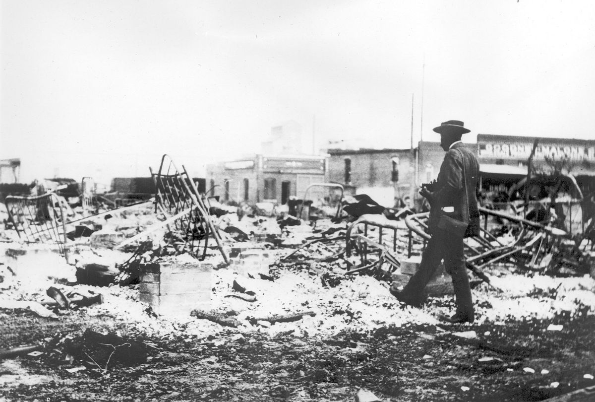 An African-American man with a camera looking at the skeletons of iron beds which rise above the ashes of a burned-out block after the Tulsa Race Massacre, Tulsa, Oklahoma, June 1921. (Oklahoma Historical Society/Getty Images)