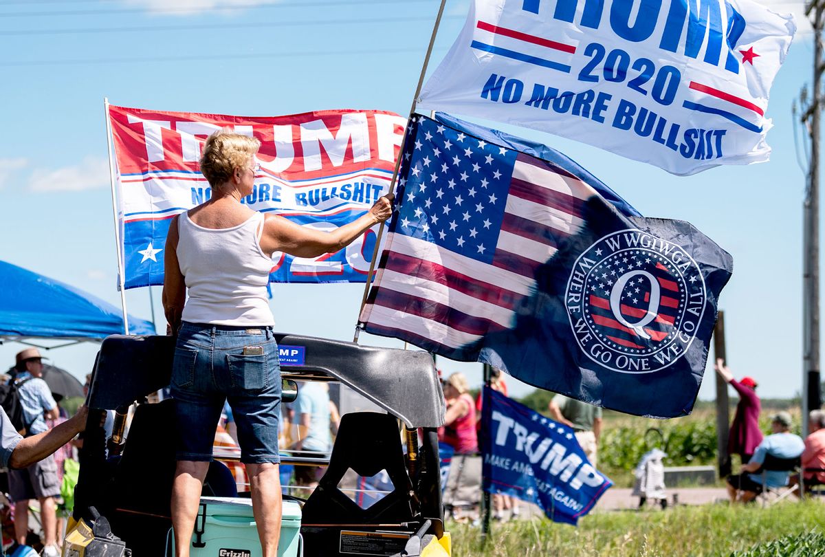 A woman holds a Trump 2020 flag and a Q Anon flag outside of Mankato Regional Airport as President Donald Trump makes a campaign stop on August 17, 2020 in Mankato, Minnesota. Trump spoke at the airport before continuing on to a campaign stop in Oshkosh, Wisconsin. (Stephen Maturen/Getty Images)
