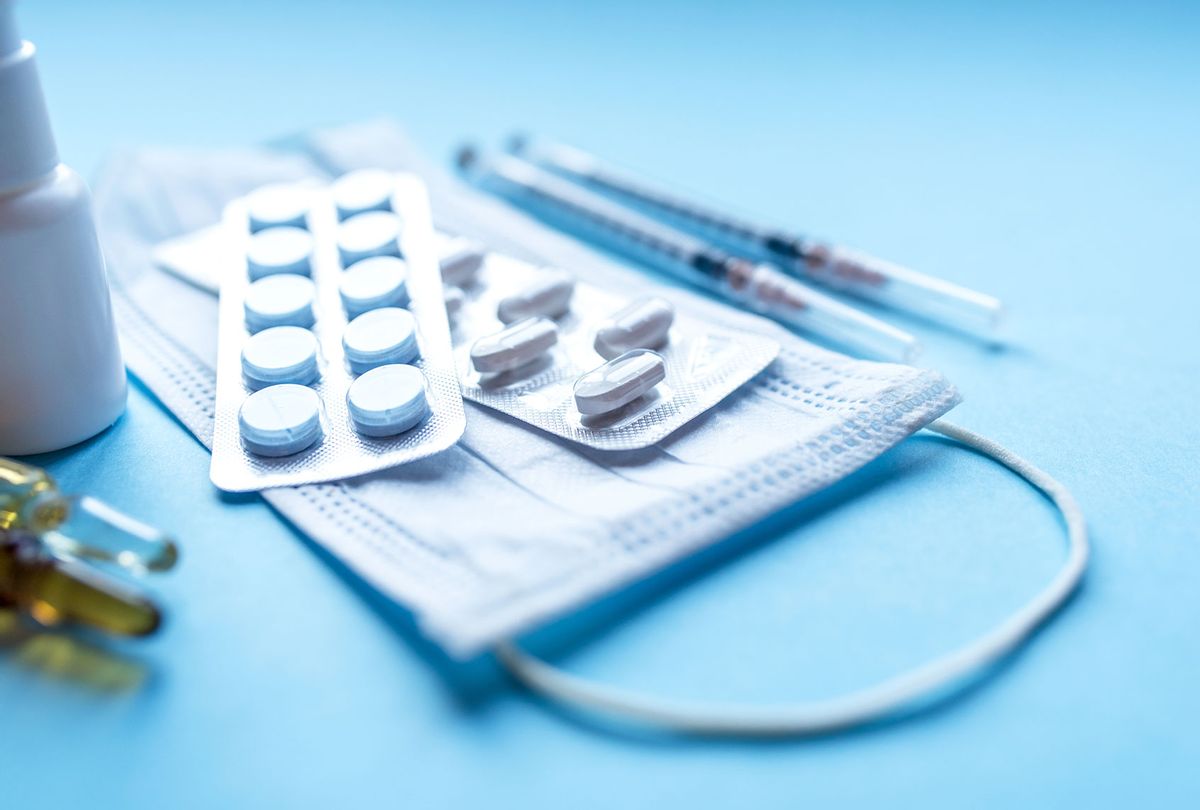 Tablets, pack of medicine, medicine bottles, syringes and a face mask on a blue background (Getty Images)