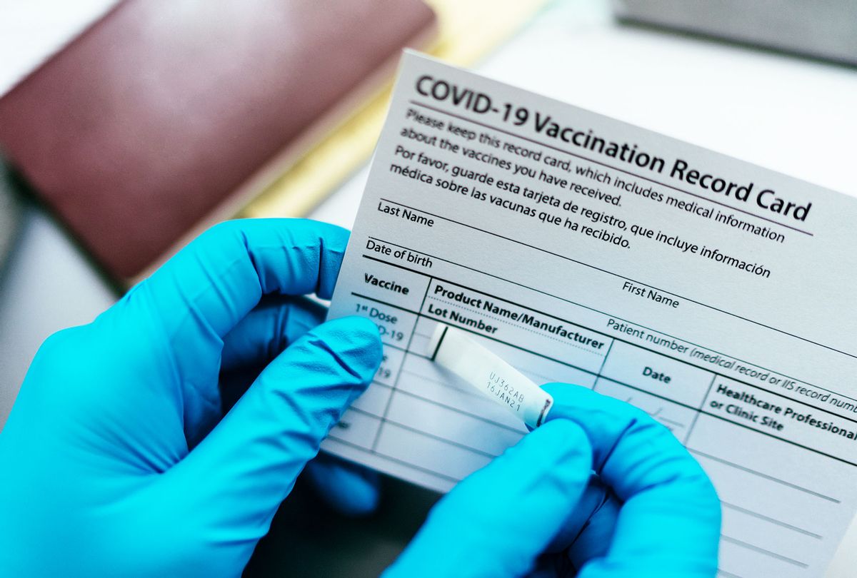 Doctor put label COVID-19 vaccine sticker on vaccination card (Getty Images)