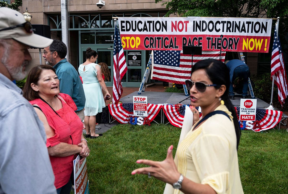 People hold up signs during a rally against "critical race theory" (CRT) being taught in schools at the Loudoun County Government center in Leesburg, Virginia on June 12, 2021. The term "critical race theory" defines a strand of thought that appeared in American law schools in the late 1970s and which looks at racism as a system, enabled by laws and institutions, rather than at the level of individual prejudices. But critics use it as a catch-all phrase that attacks teachers' efforts to confront dark episodes in American history, including slavery and segregation, as well as to tackle racist stereotypes. (ANDREW CABALLERO-REYNOLDS/AFP via Getty Images)