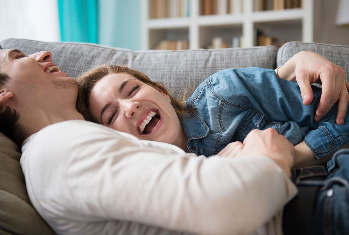 Couple laughing together on couch (Jamie Grill/Getty Images)
