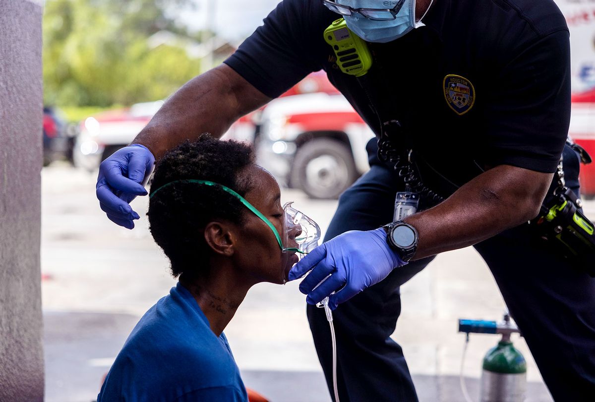 Houston Fire Department EMS supervisor Michael Norwood gives oxygen to a woman with suspected Covid-19 before transporting her to a hospital for treatment on August 20, 2021 in Houston, Texas. (John Moore/Getty Images)