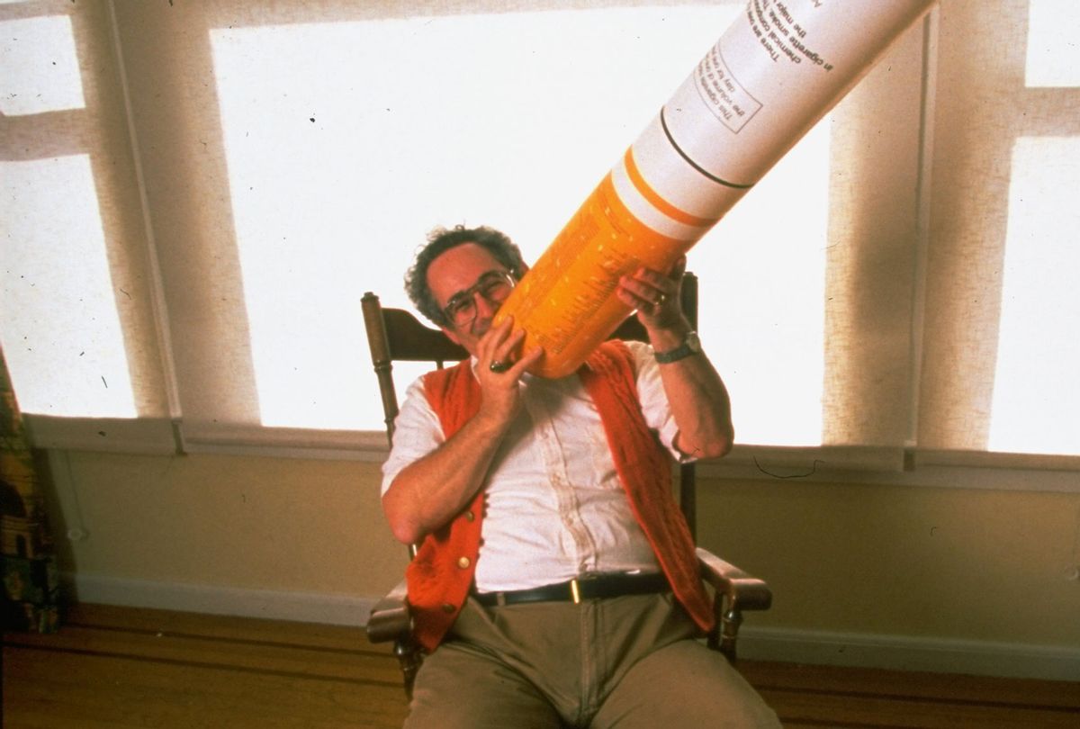 Author & antismoking advocate Stanton Glantz holding giant fake cigarette up to his mouth as he sits in rocking chair at home. (John Storey/Getty Images)