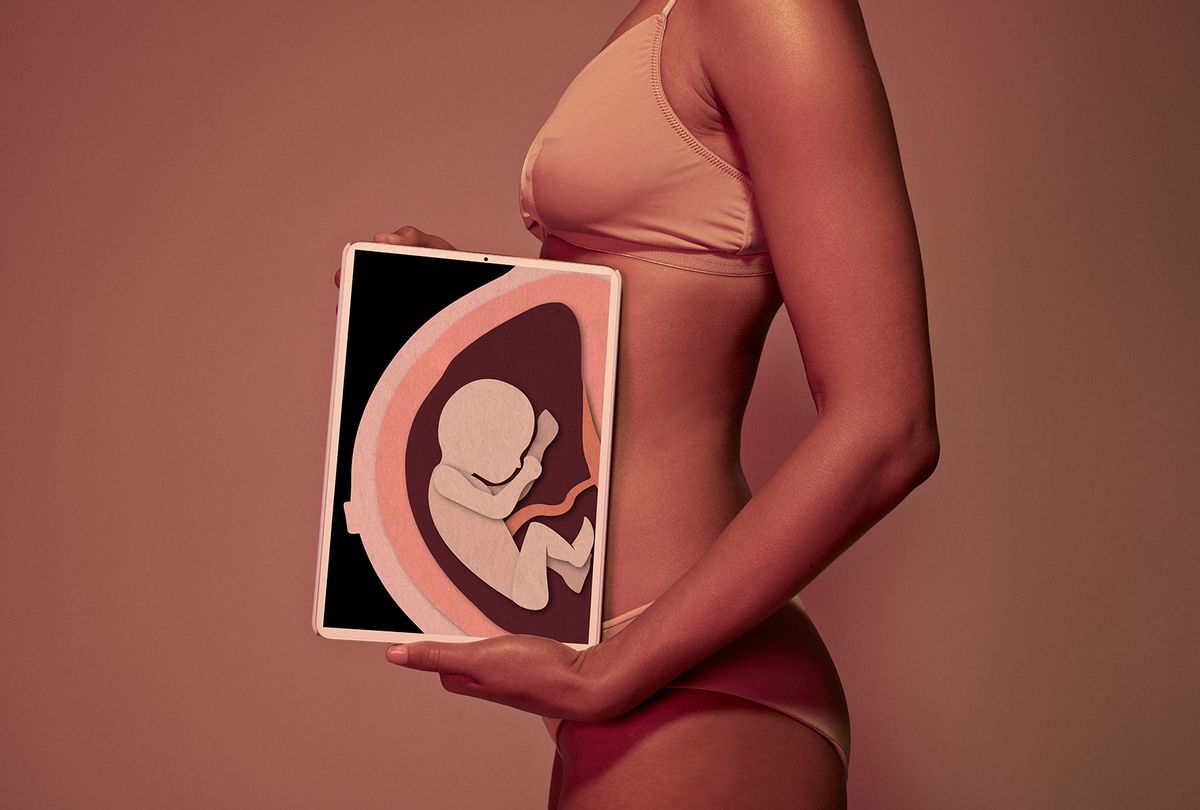Female holding tablet in front of body to display coloured x-ray illustrations of a pregnancy (Klaus Vedfelt/Getty Images)