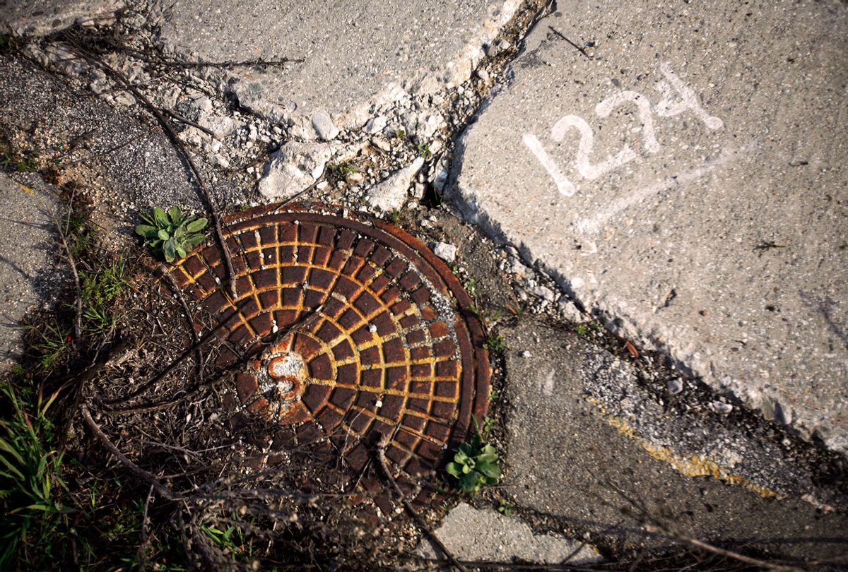 Rusted manhole cover in the cement of an abandoned street (Bob Chamberlin/Los Angeles Times via Getty Images)