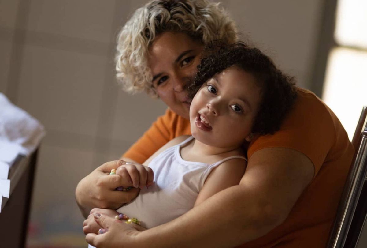 Rochelle dos Santos embraces her daughter, who was born with microcephaly in 2016 after dos Santos contracted Zika during her pregnancy in midwest Brazil. (Ueslei Marcelina for Undark)