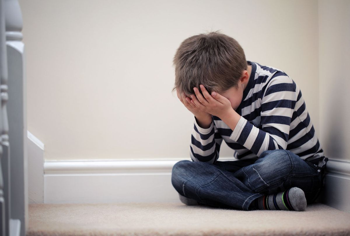 Upset child with head in hands sitting on staircase (Getty Images/BrianAJackson)