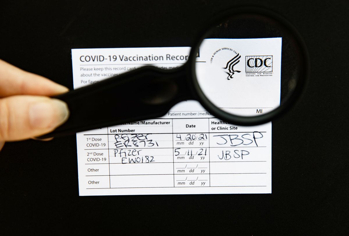 A photo of a hand using a magnifying glass to check the authenticity of s Covid-19 vaccine card (Raychel Brightman/Newsday RM via Getty Images)