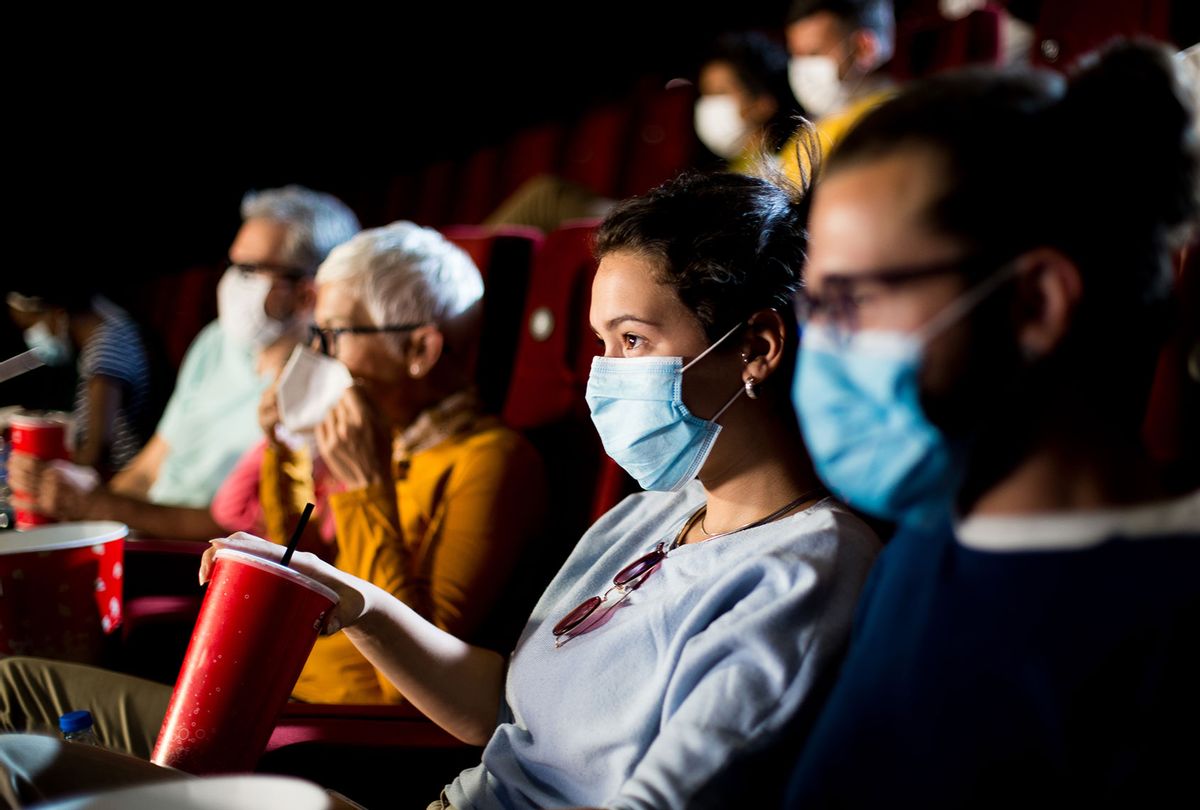 Young couple with protective face masks watching the movie at the cinema and enjoying (Getty Images/MixMedia)