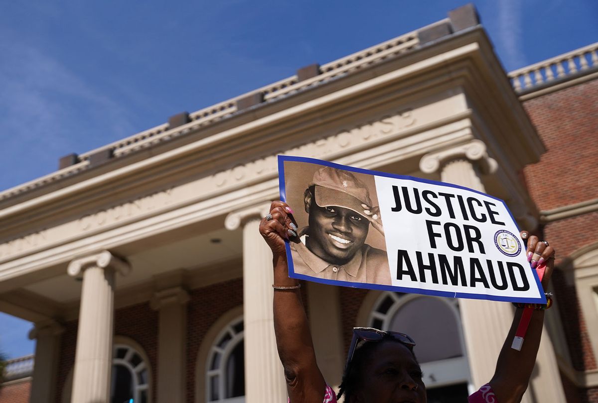 A demonstrator holds a sign at the Glynn County Courthouse as jury selection begins in the trial of the shooting death of Ahmaud Arbery on October 18, 2021 in Brunswick, Georgia. Three white men are accused of chasing down and murdering Arbery in southeastern Georgia last year. (Sean Rayford/Getty Images)