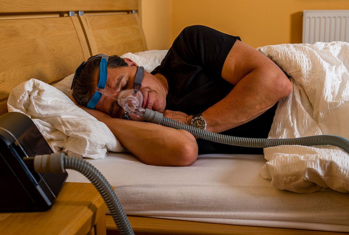 Man sleeping with cpap mask because of obstructive sleep apnea (Getty Images/no_limit_pictures)