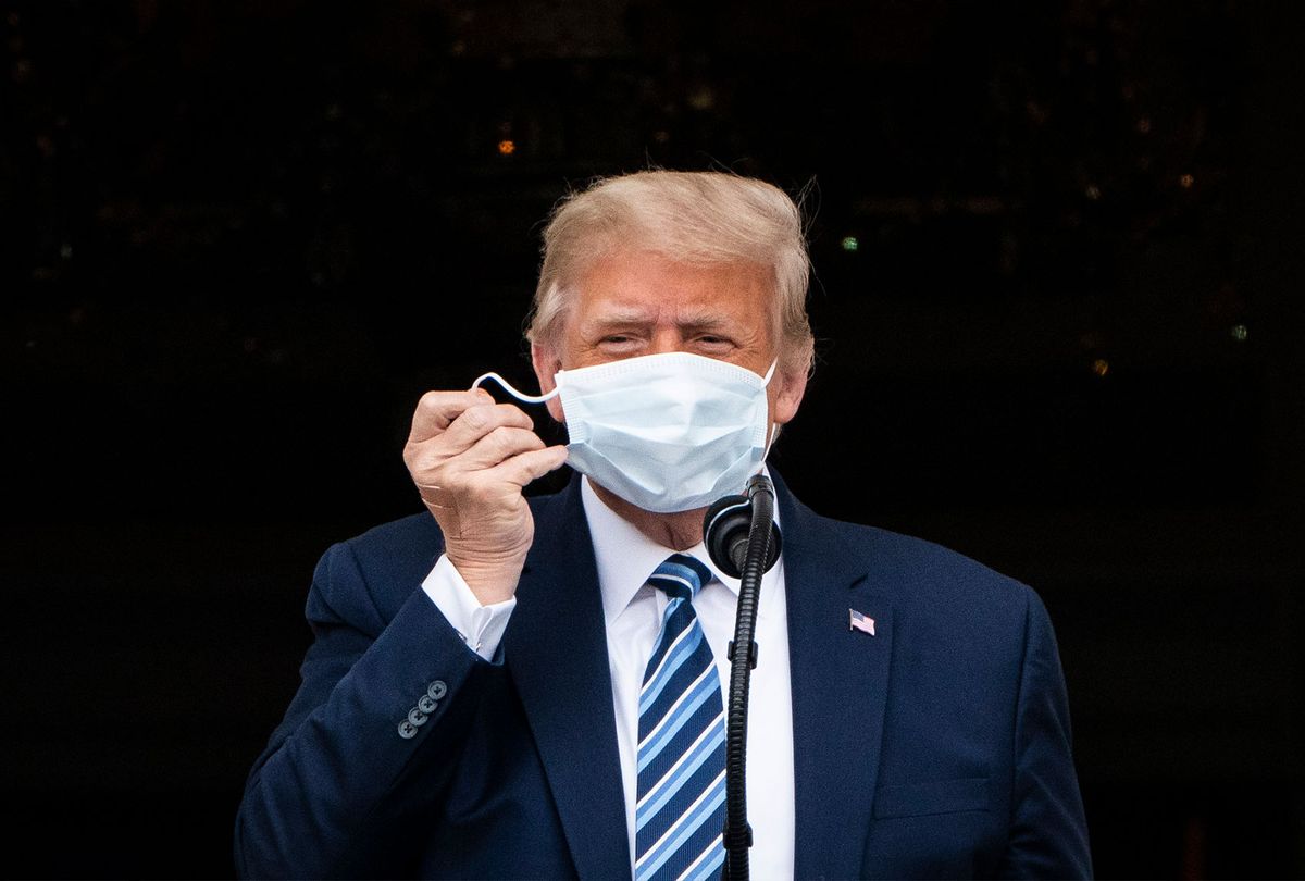 Donald J. Trump, with a bandage in his hand, removes his face mask as he arrives to speak to supporters from the Blue Room balcony during an event at the White House on Saturday, Oct 10, 2020 in Washington, DC.  (Jabin Botsford/The Washington Post via Getty Images)