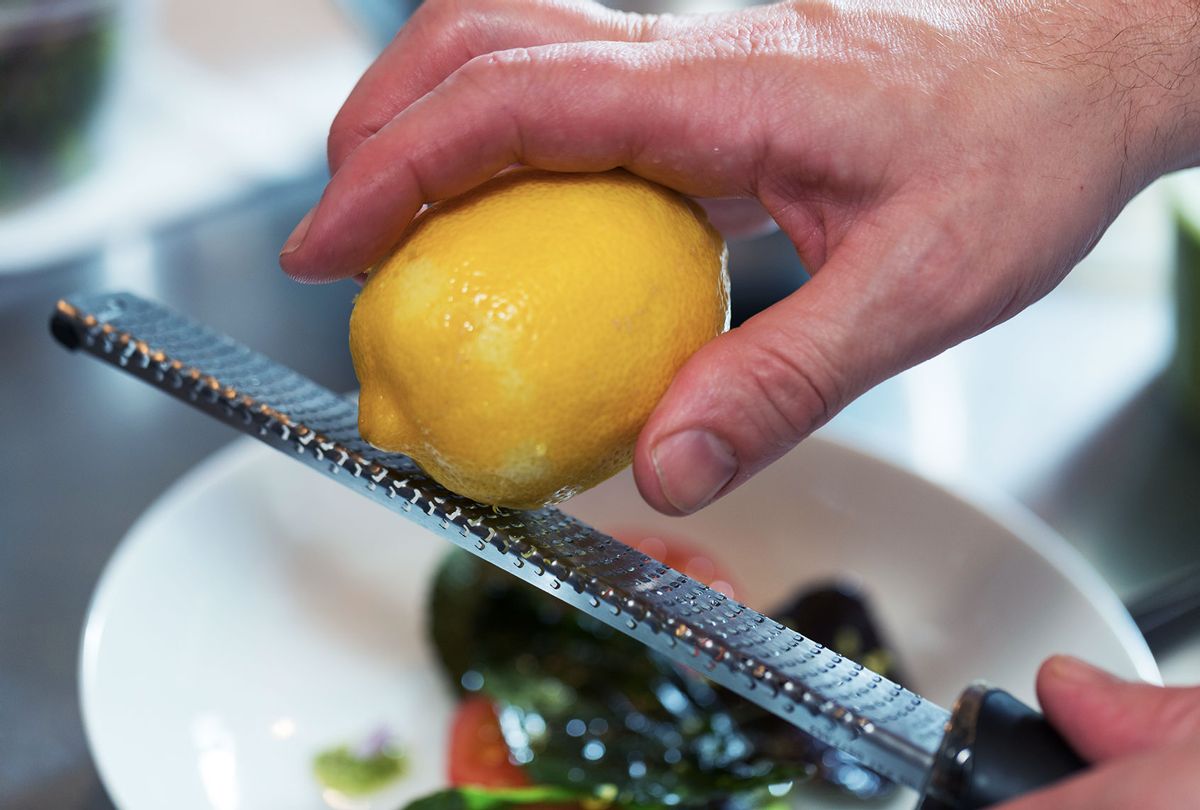 Zesting the peel of a lemon on a microplane grater (Getty Images/Jon Lovette)