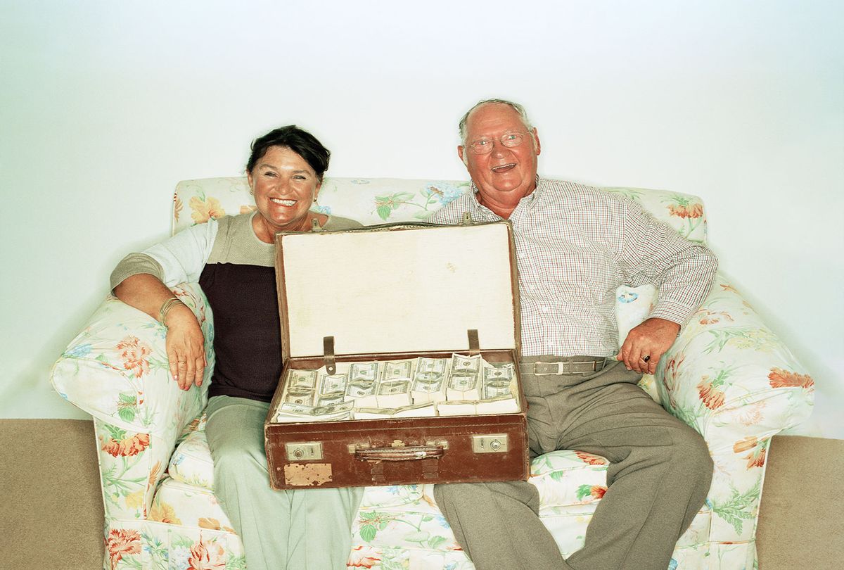 Mature couple on the sofa with a suitcase full of money (Getty Images/Daly and Newton)