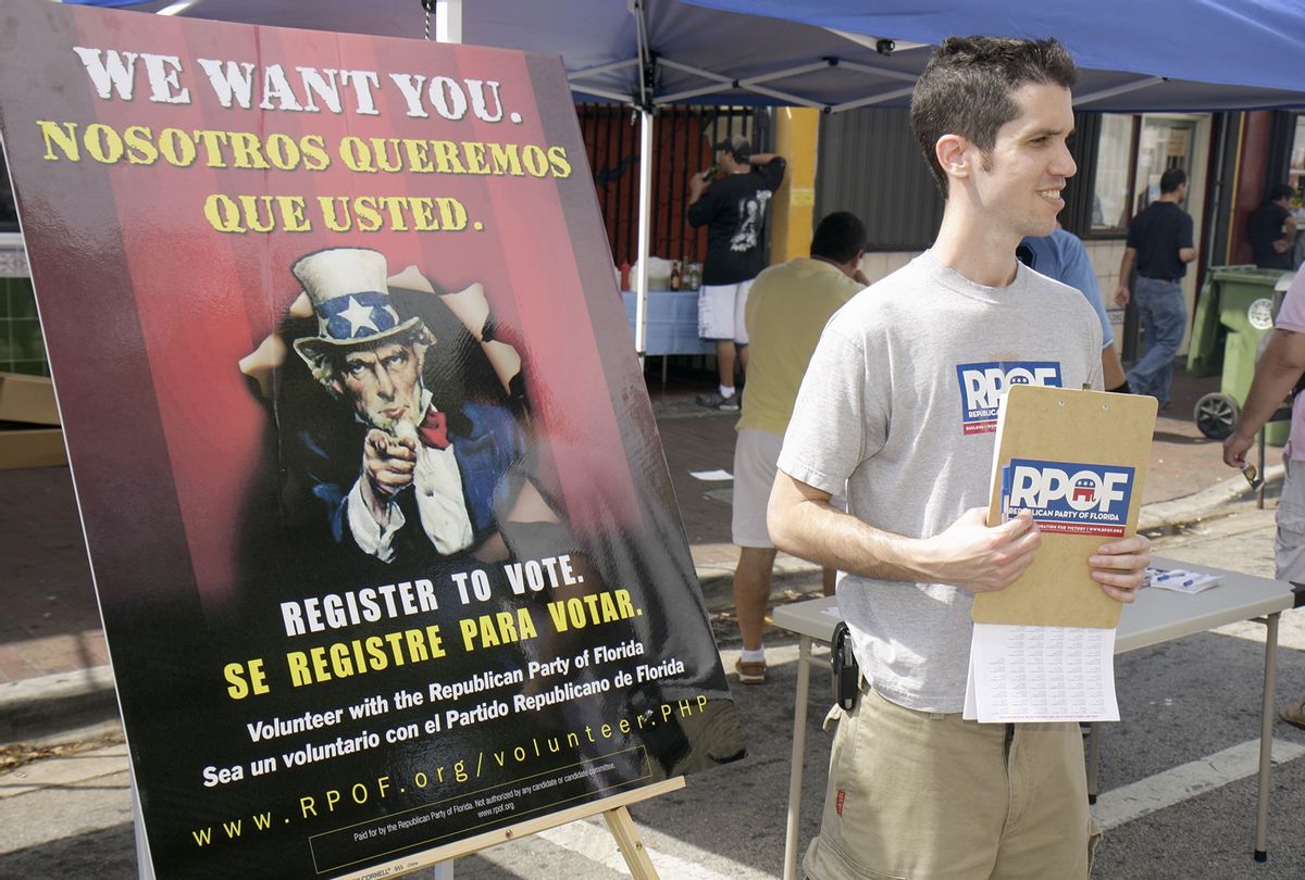 A Republican Party volunteer standing next to a voter registration poster at Carnival Miami. (Jeffrey Greenberg/Universal Images Group via Getty Images)